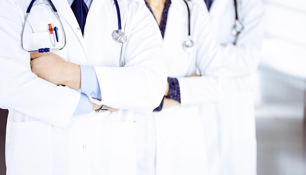 Group of modern doctors standing as a team with crossed arms and stethoscopes in hospital office. Physicians ready to examine and help patients. Medical help, insurance in health care, best desease tr