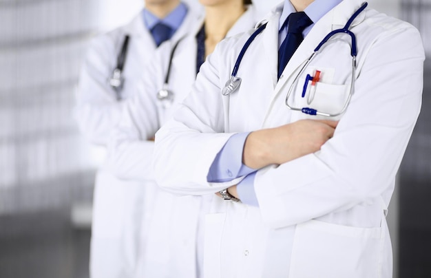 Group of modern doctors standing as a team with crossed arms\
and stethoscopes in hospital office. physicians ready to examine\
and help patients. medical help, insurance in health care, best\
desease tr