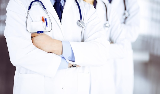 Group of modern doctors standing as a team with crossed arms\
and stethoscopes in hospital office. physicians ready to examine\
and help patients. medical help, insurance in health care, best\
desease tr