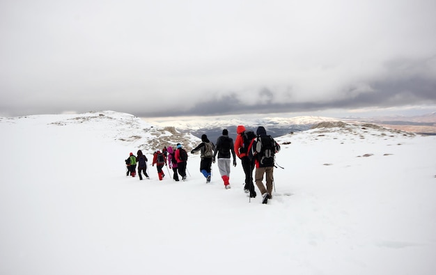 Foto gruppo di alpinisti che camminano attraverso le montagne coperte di nevexaxa