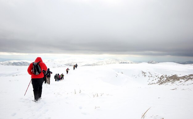 snowxAxAで覆われた山々を歩く登山家のグループ