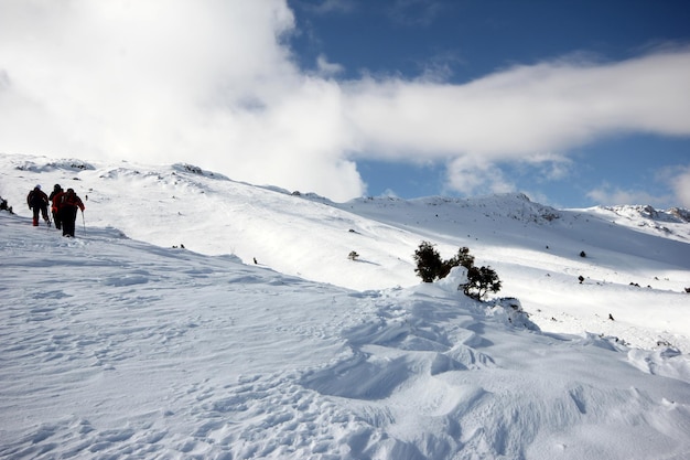 snowxDxAで覆われた山を歩く登山家のグループ