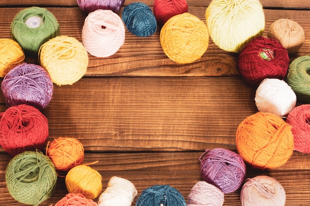 Group of multi-colored woolen clews on a wooden background.