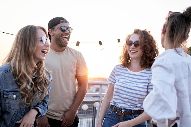 Group of multi ethnicity friends laughing at the party in top of the roof