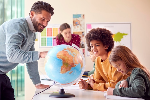 Foto gruppo di studenti multiculturali con insegnanti in aula guardando il globo nella lezione di geografia