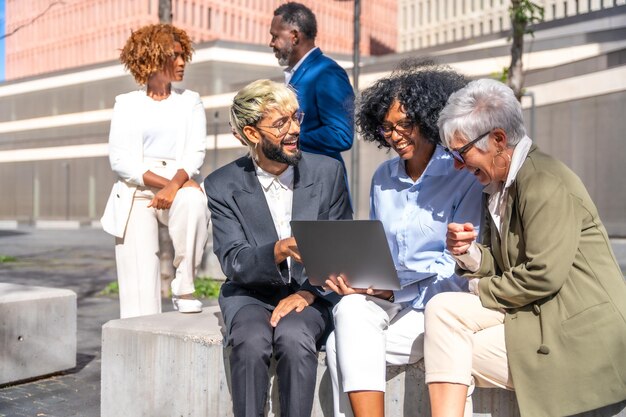 Group of multiethnic business people using laptop sitting outdoors