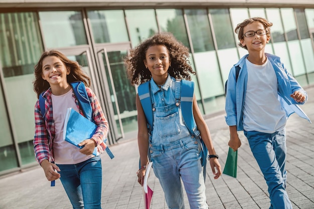 Foto gruppo di bambini multietnici delle scuole elementari che camminano dopo le lezioni scolastiche all'aperto