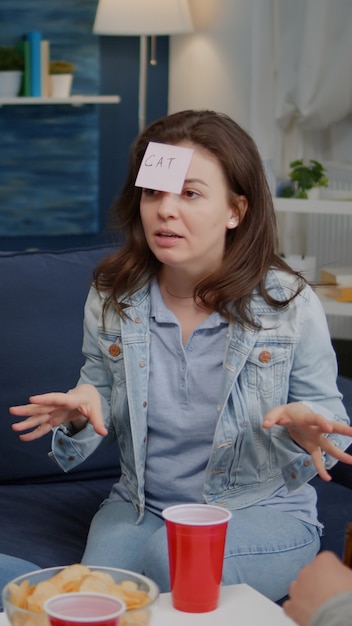 Group of multiethnic friends spending time together playing guess who game using sticky notes