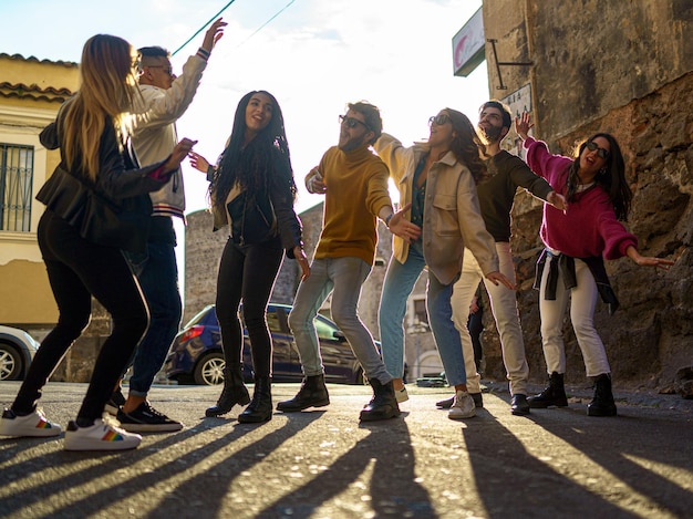 group of multiethnic happy friends having fun on weekend dancing together in the streets