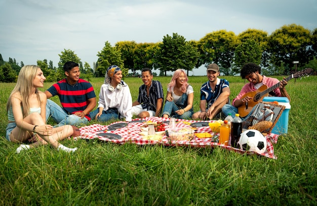 Группа мультиэтнических подростков проводит время на открытом воздухе на пикнике в парке