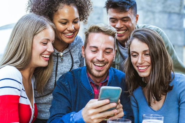 Group of multiracial friends having fun using social network, tech people and young influencer creating digital content with smart phone and mobile app