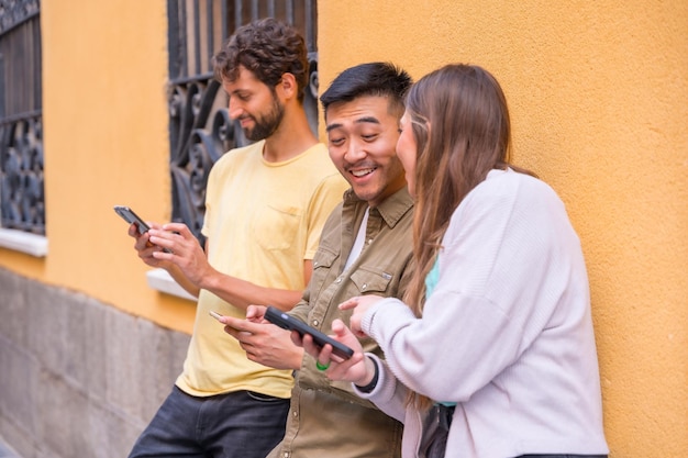 Group of multiracial friends looking smiling at the phone in the city