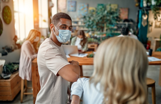 Photo group of multiracial people working in modern office during coronavirus. young business people and senior boss are working together wearing face protective masks. preventive measures during covid-19