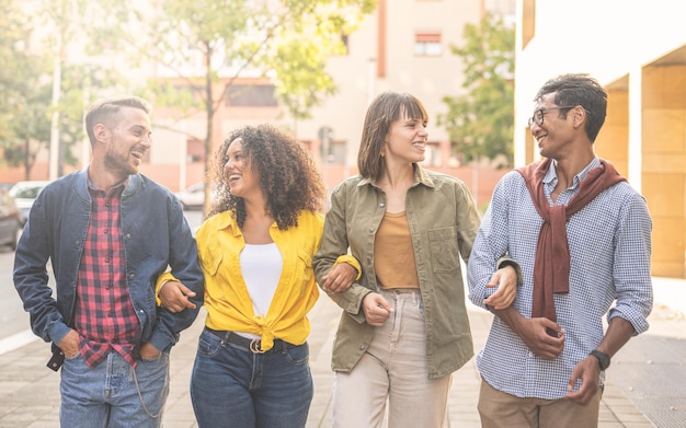 Group of multiracial students walking in the city, young people
smling and laughing while having a break of university lesson, warm
light effect