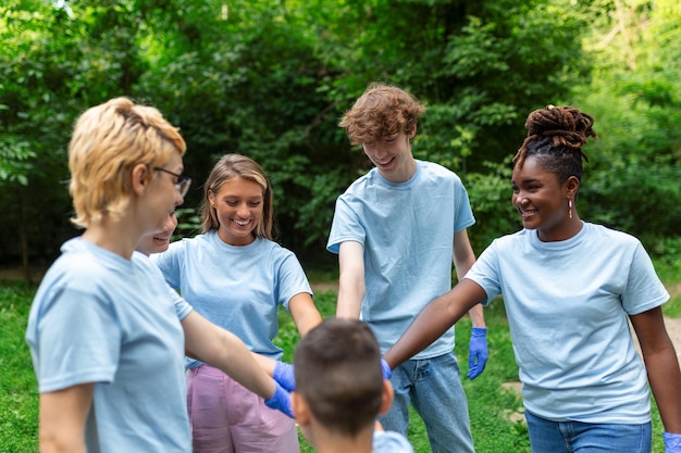 다민족 자원봉사자 젊은이 그룹이 공원에서 야외에서 팀을 만들고 함께 손을 잡습니다.