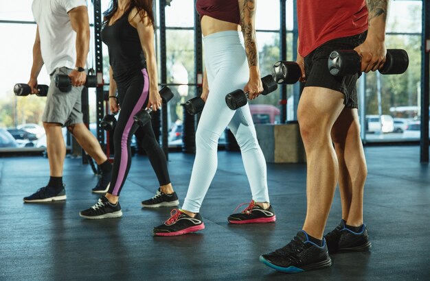 Un gruppo di atleti muscolosi che si allenano in palestra. ginnastica, allenamento, flessibilità di allenamento fitness. stile di vita attivo e sano, gioventù, bodybuilding. allenamento in esercizi con pesi.