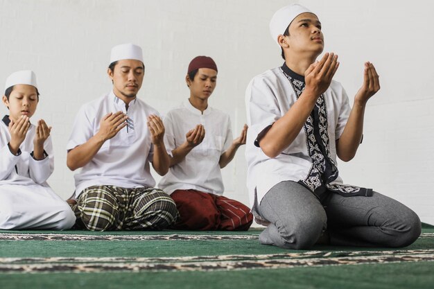 A group of Muslim men praying after salat by the imam at the mosque