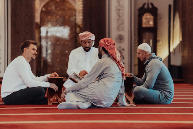 Photo a group of muslims reading the holy book of the quran in a modern mosque during the muslim holiday of ramadan.