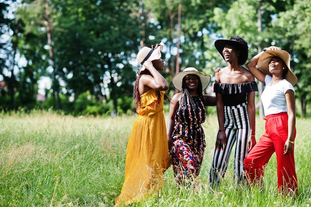 Фото Группа из четырех великолепных женщин в летних шляпах, проводящих время на зеленой траве в парке