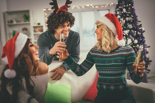 写真 家でクリスマスを祝う友達のグループは、ビールを楽しんで楽しんでいます。