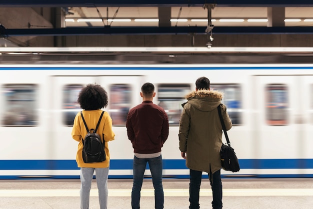 Фото Группа друзей в ожидании поезда на платформе станции метро. концепция общественного транспорта.