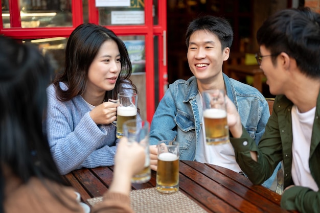 写真 幸せなアジア人友達のグループが街のレストランやバーで一緒にビールを飲んでいます