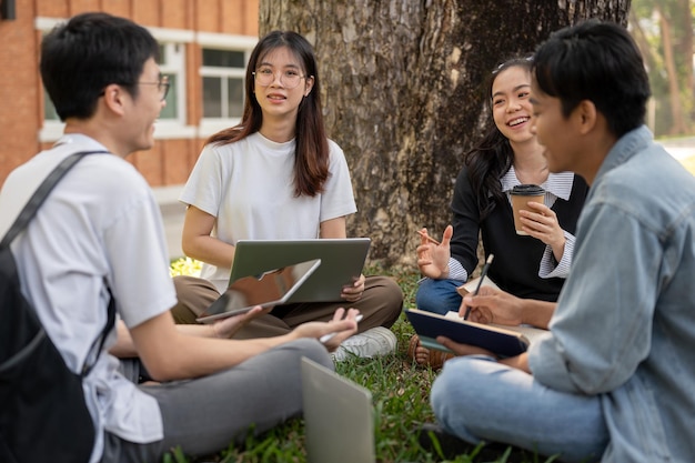 사진 행복 한 젊은 십대 아시아 학생 들 의 그룹 은 캠퍼스 공원 에서 함께 이야기 하고 숙제를 하고 있다