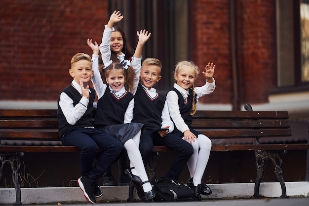Фото Группа детей в школьной форме, которая на открытом воздухе вместе возле здания образования.