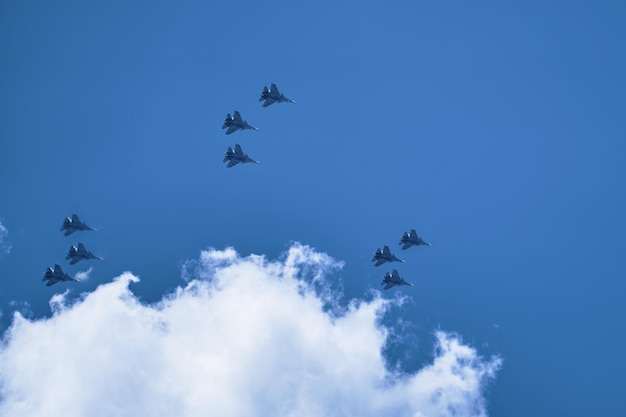 写真 軍用航空機のグループは ⁇ 雲の背景に青い空で飛行技を演じ ⁇ 軍のパレードを行っています ⁇