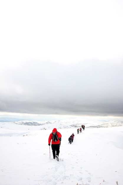 写真 snowxaxaで覆われた山々を歩く登山家のグループ