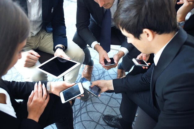 写真 会議に座ってスマートフォンを使用している人々のグループ。