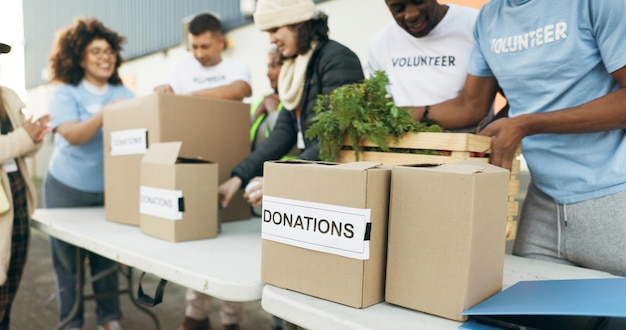 写真 ボランティアと食料の箱をテーブルの上に置く 慈善活動   優しさと信頼  コミュニティの寄付 ngoの男性と女性 非営利のプロジェクトで食料品パッケージの配布
