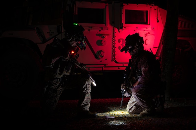사진 위장 유니폼 을 입은 군인 들 의 집단 이 밤 에 순찰 임무 를 수행 하는 무기 를 들고 있다