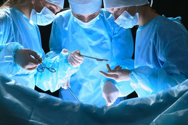 写真 青を基調とした手術室で働く外科医のグループ