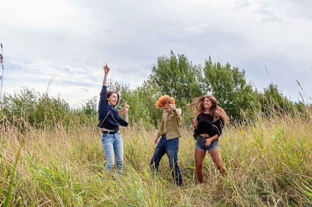 Фото Группа из трех друзей, мальчика и двух девочек, танцующих и веселых вместе на открытом воздухе