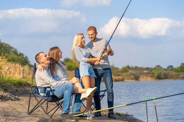 Группа молодых друзей, рыбалка на пирсе у озера