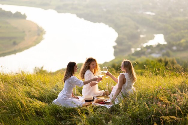 写真 夏の夕方草の上に座っている若い女性のグループ