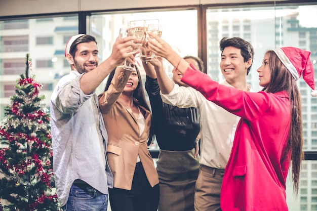 Group of office workers celebrating Christmas and New Year with clink glasses and drink wine together with happy and smile in office. Concept of the celebration of the company party.