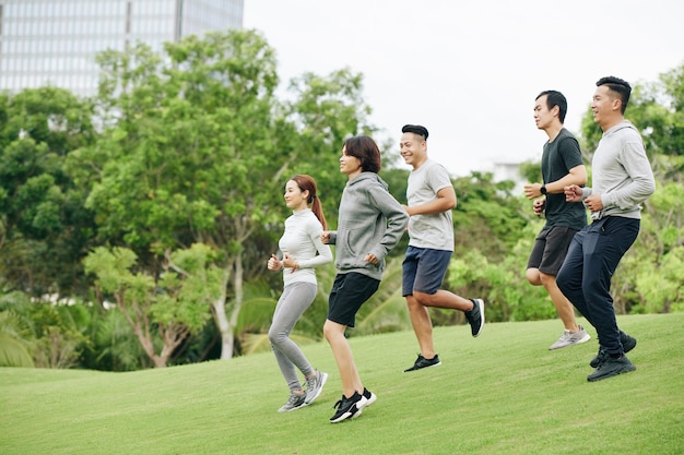 都市公園でトレーニングするときに丘を駆け下りる若いベトナム人スポーツマンのグループ