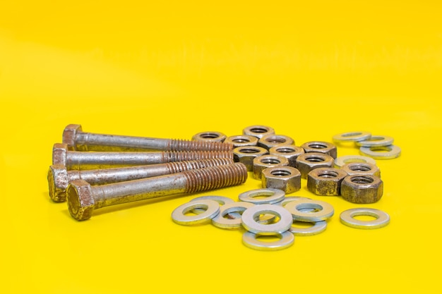 Group of old rusty bolts, washers and nuts on yellow background fixing elements. stock photo