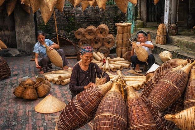 Photo group of old vietnamese female craftsman making the traditional bamboo fish trap