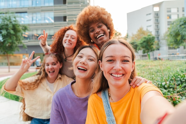 Group of only young multiracial women taking a selfie with a smartphone to share on social media