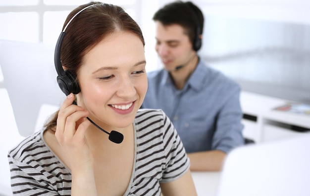 Group of operators at work Call center Focus on beautiful woman receptionist in headset