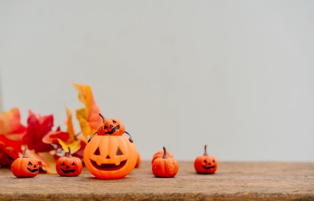 group of orange spooky pumpkins and maple leaves on brown retro wood tabletop background for design