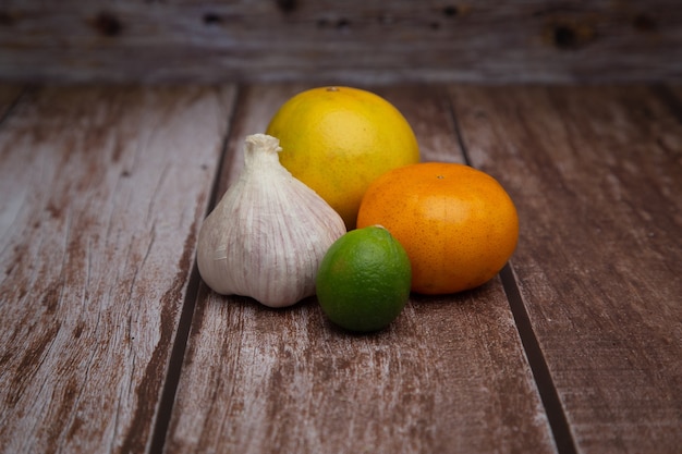 Photo group of an orange, tangerine, garlic and lemon with wooden background