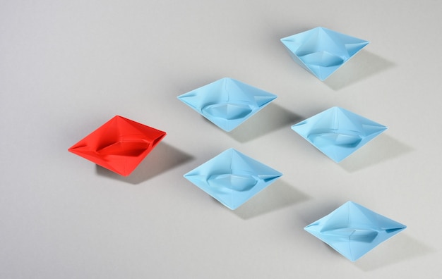 Group of paper boats on a gray surface. concept of a strong leader in a team, manipulation of the masses, following new perspectives, collaboration and unification. Startup