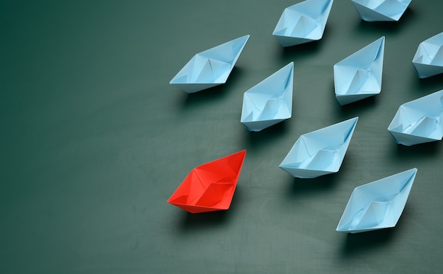 Group of paper boats on a green surface. concept of a strong leader in a team, manipulation of the masses, following new perspectives, collaboration and unification. Startup