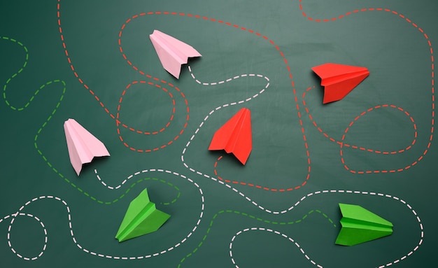 Group of paper planes with long tangled paths on a green\
background. concept of a strong leader with extraordinary thinking,\
quick decision-making. finding the optimal and simple solution in\
business