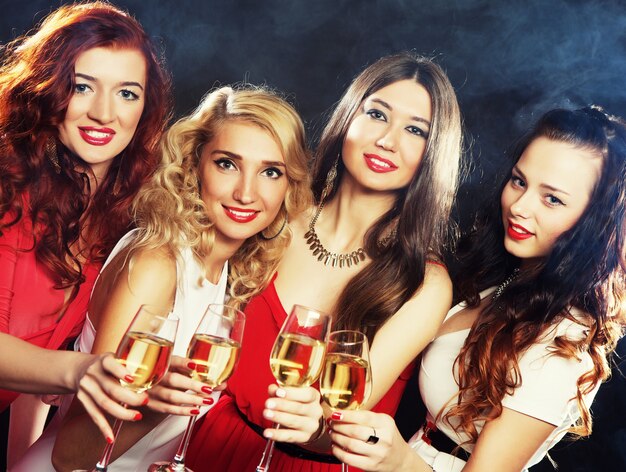 Photo group of partying girls clinking flutes with sparkling wine
