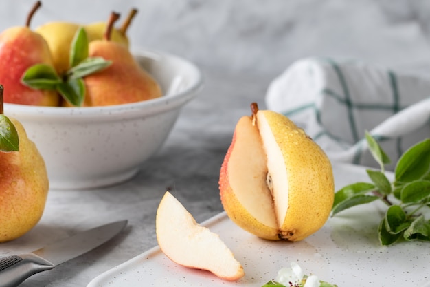 A group of pears and pear pieces on a white cutting Board on a concrete background